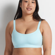 Woman wearing the aqua blue Alive Bandeau Bra with matching briefs, standing against a grey wall.