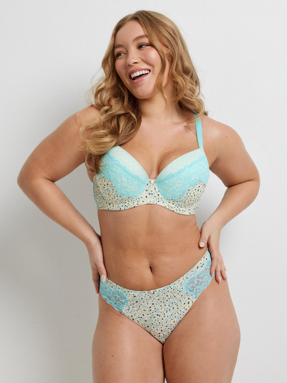 A woman wearing a cream loral bra with blue lace detail