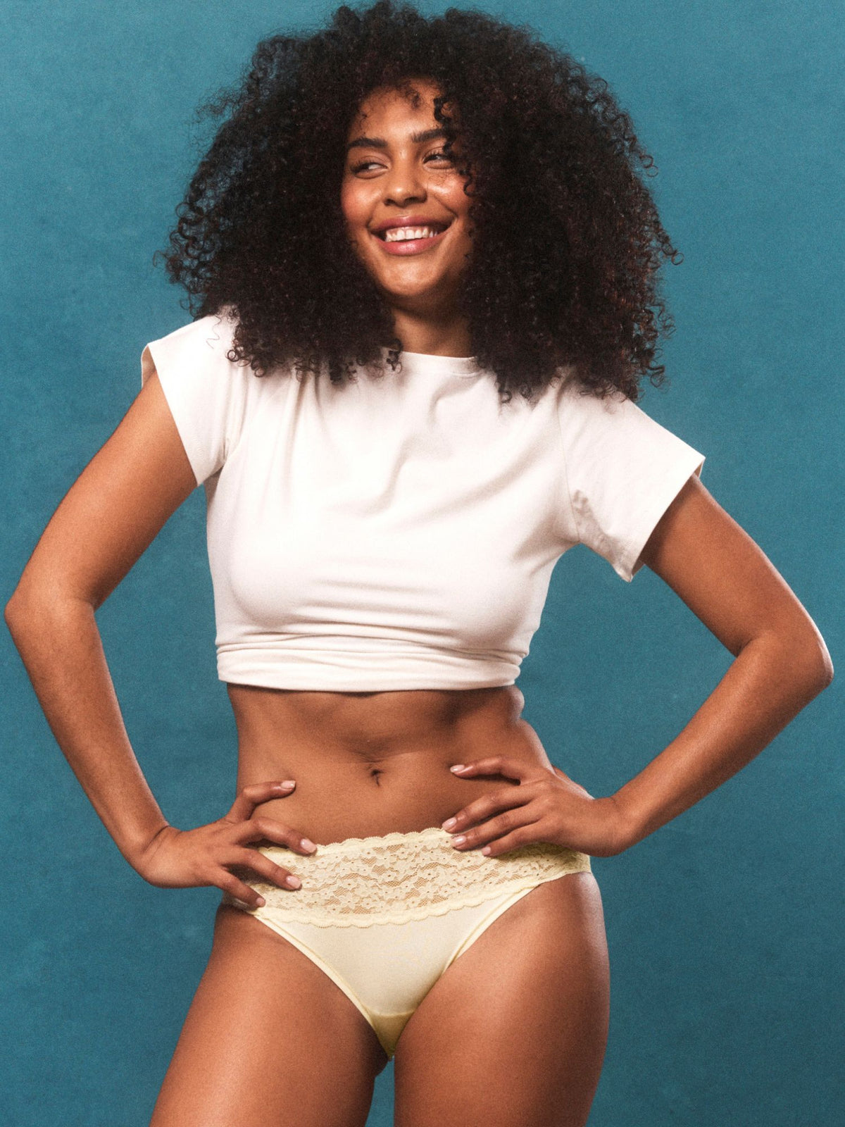 Campaign lifestyle image featuring model Jaida in Glowlights Bikini Brief in Lemon Icing styled with a white t-shirt.