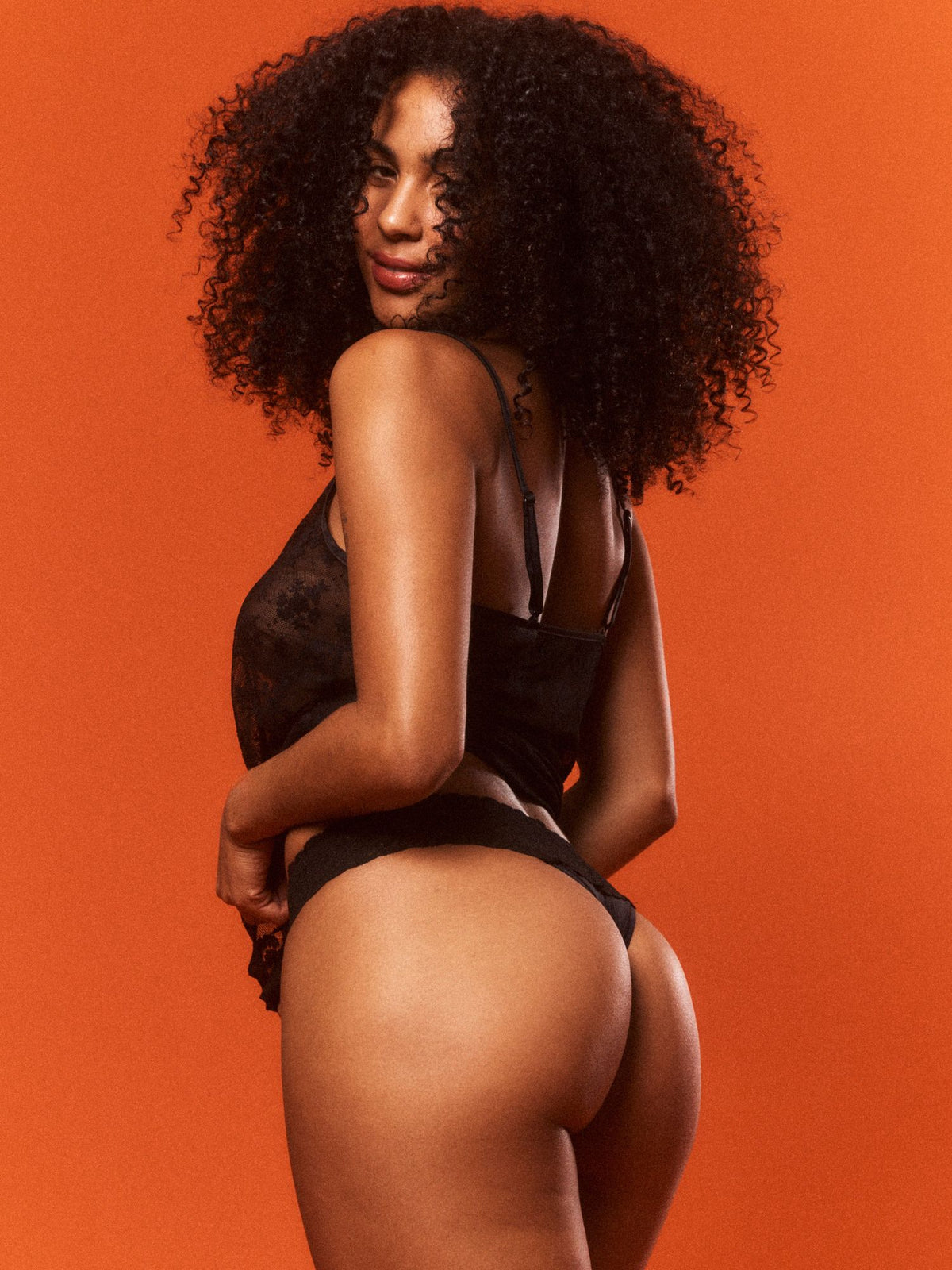 Woman in black lingerie against an orange background