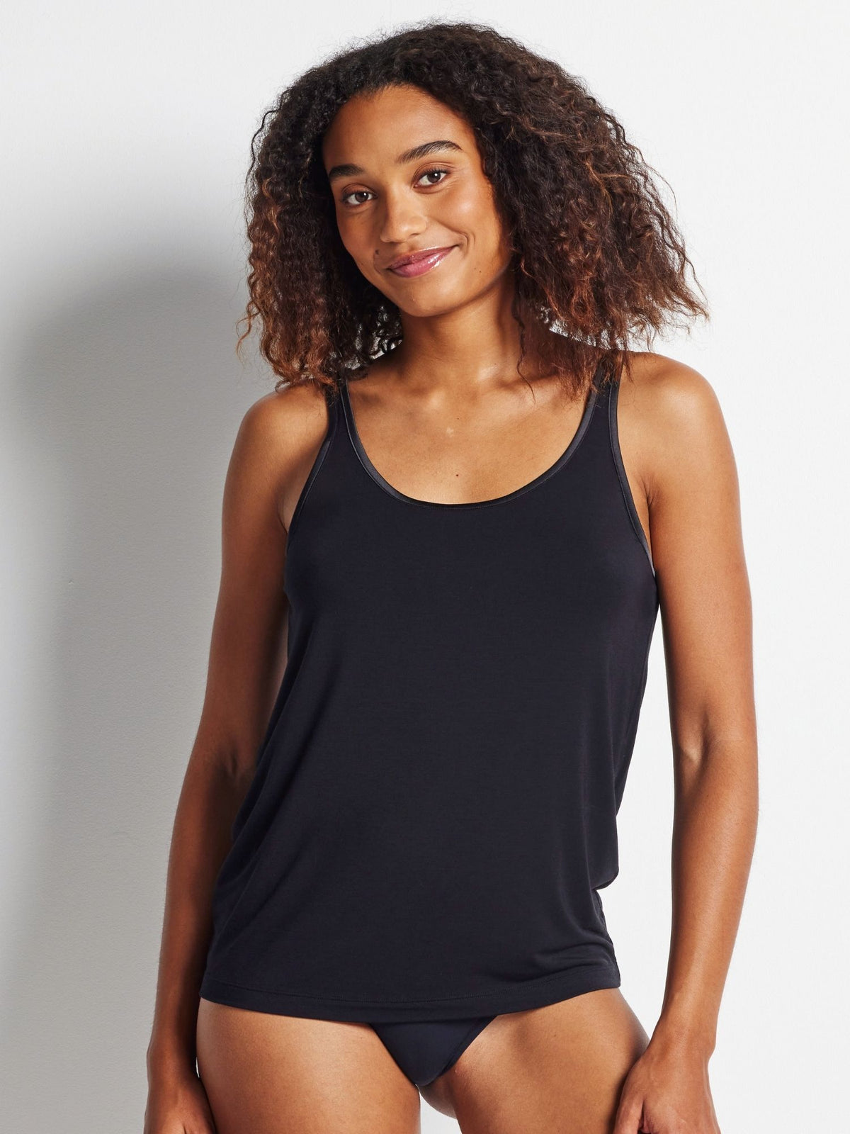 Woman wearing a black tank top against a plain background