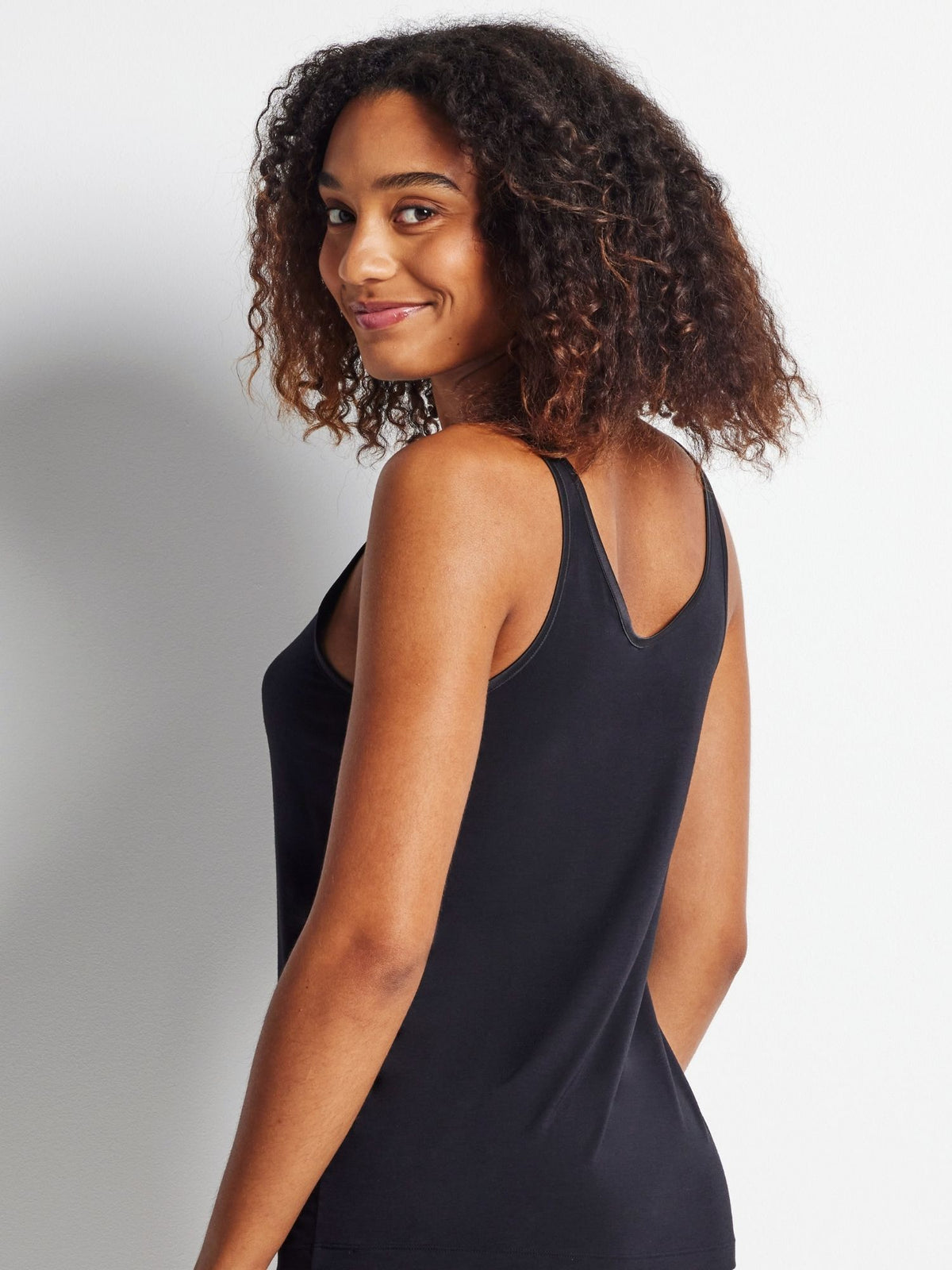 Woman wearing a black sleeveless top against a plain background