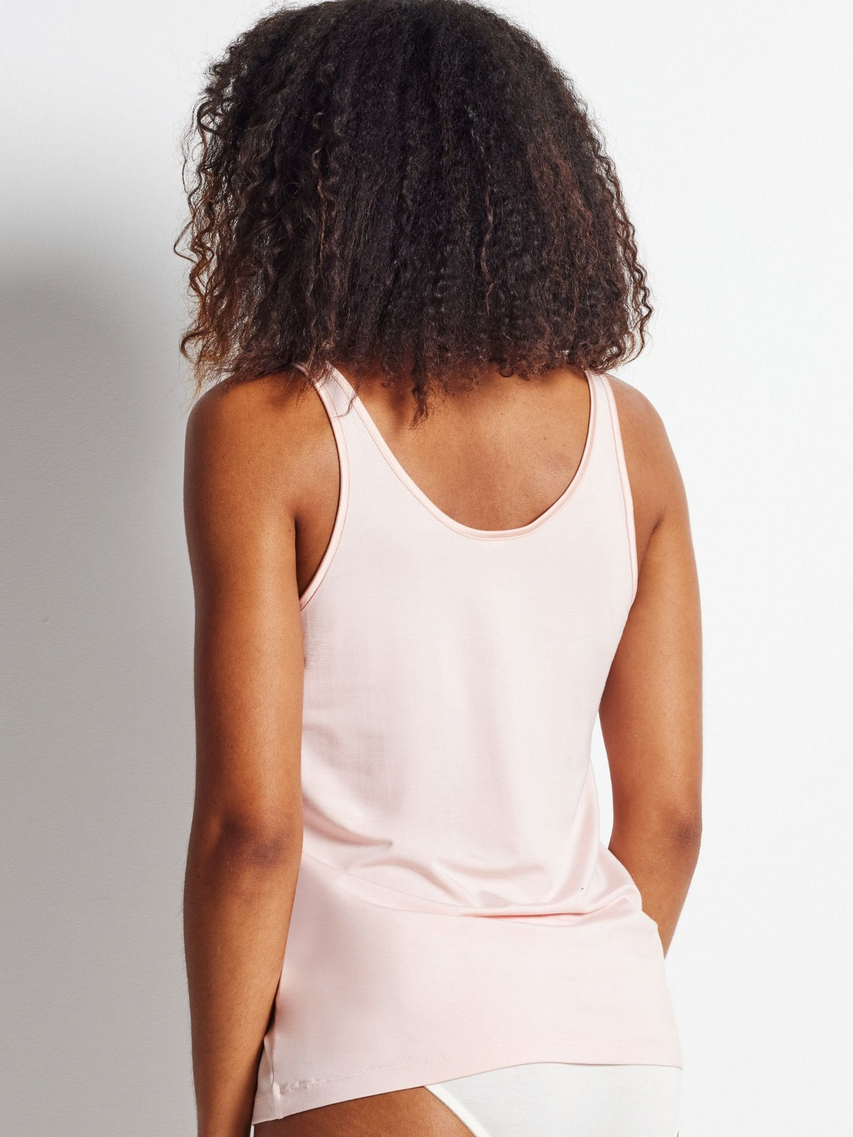 Person wearing a light pink tank top against a plain background