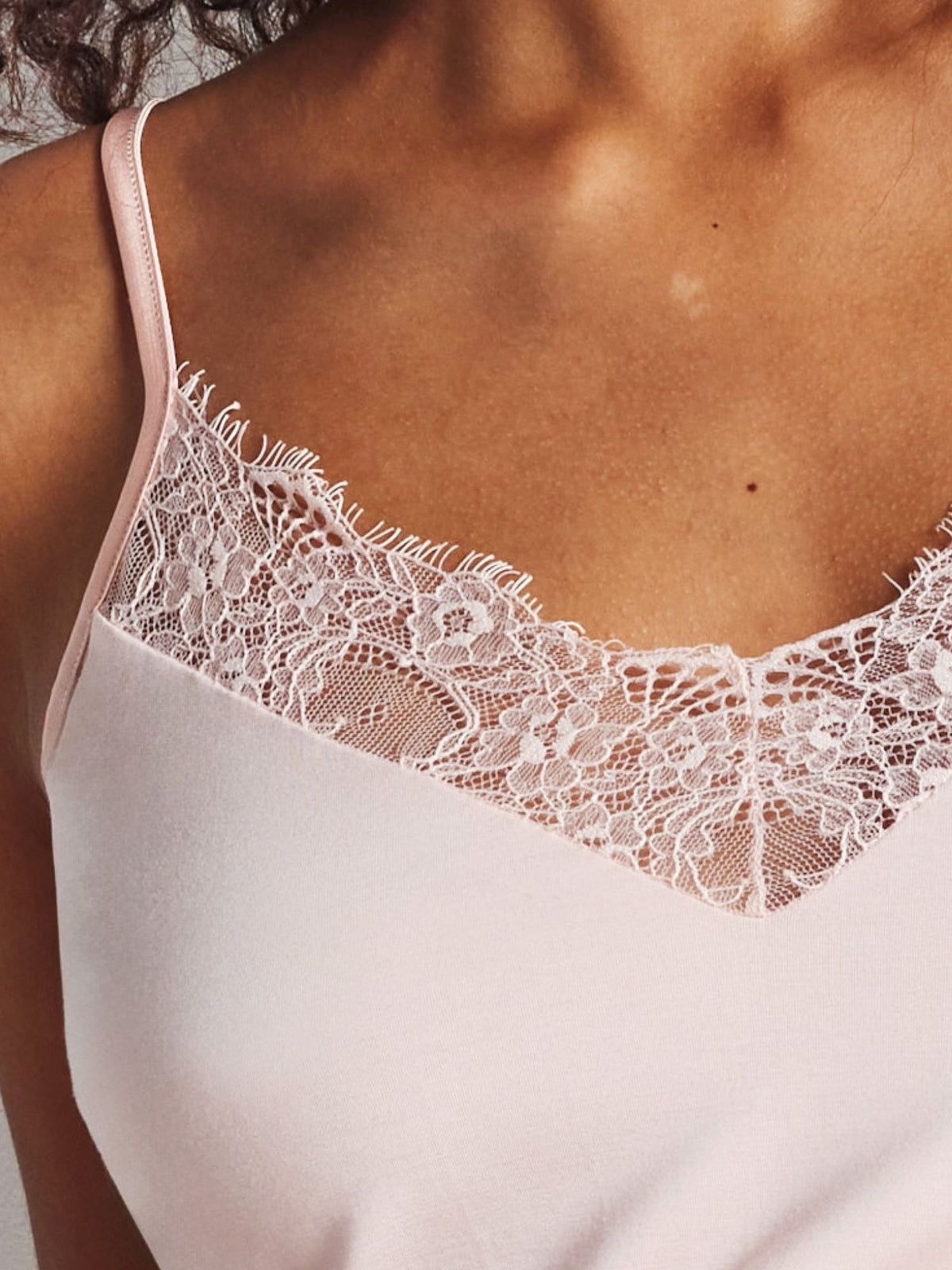 Close-up of a white lace-trimmed camisole worn by a person.