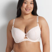Chloe is wearing the Be Free Lace Balconette Bra in Shell with matching briefs, standing against a grey wall.