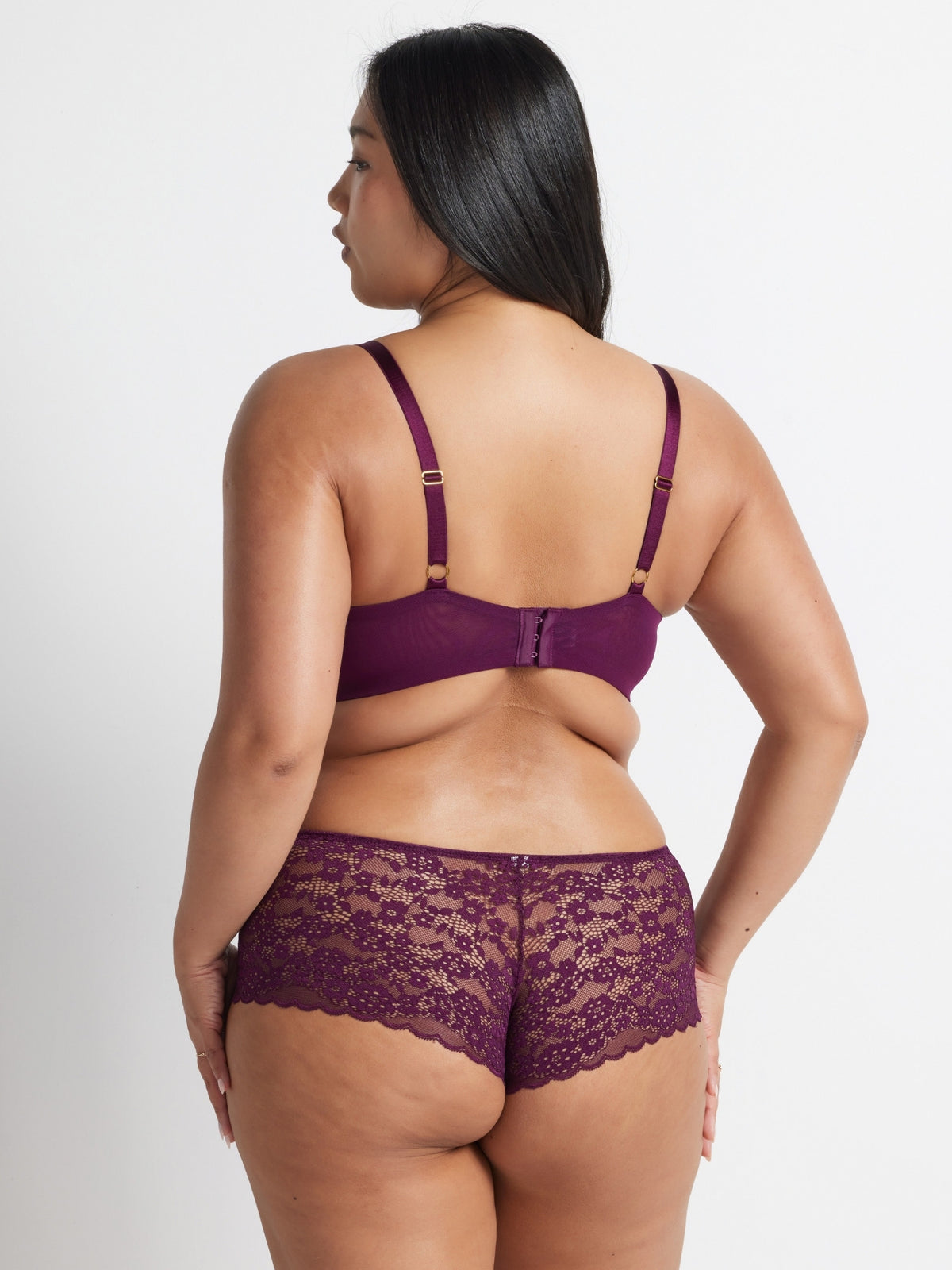 Back view of model wearing the burgundy lace short and matching bra set against a light background.
