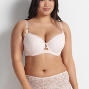 Chloe is wearing the Be Free Lace Short in Shell with matching bra, standing against a grey wall.