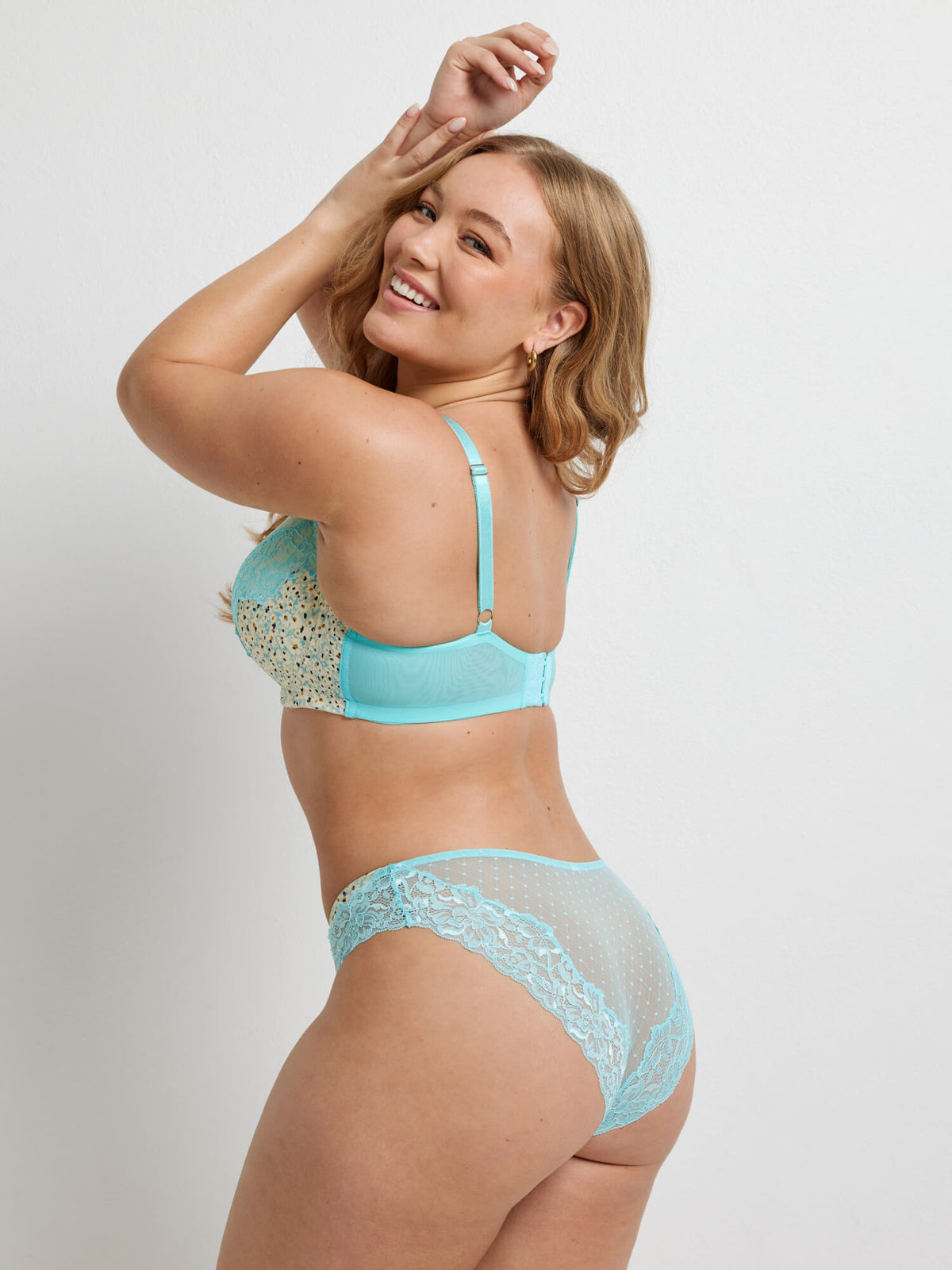 A woman wearing a cream and blue floral underwear brief with blue lace detail.