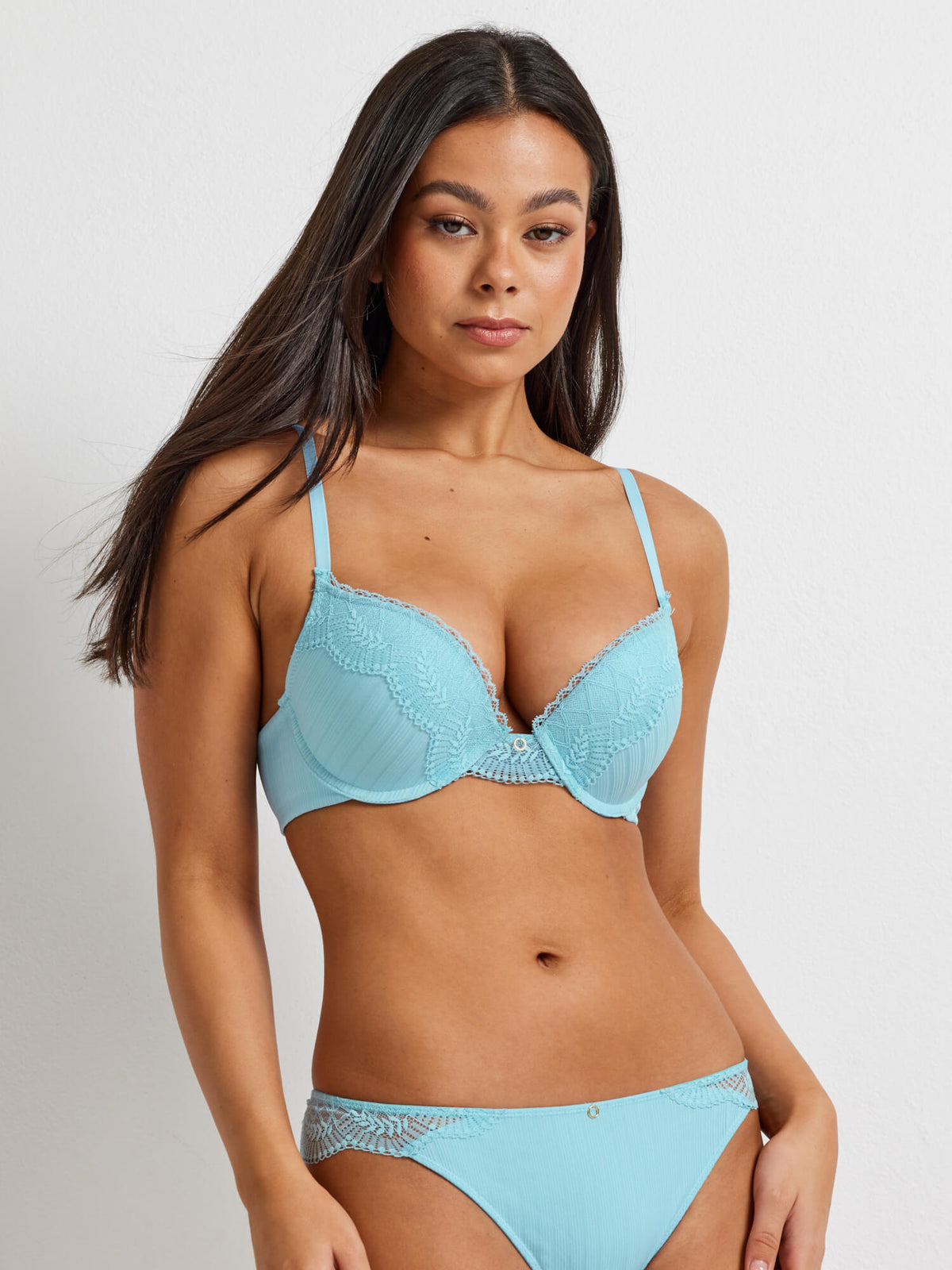 A woman wearing a turquoise blue push up bra featuring ribbed fabric and lace detail on the cups. 