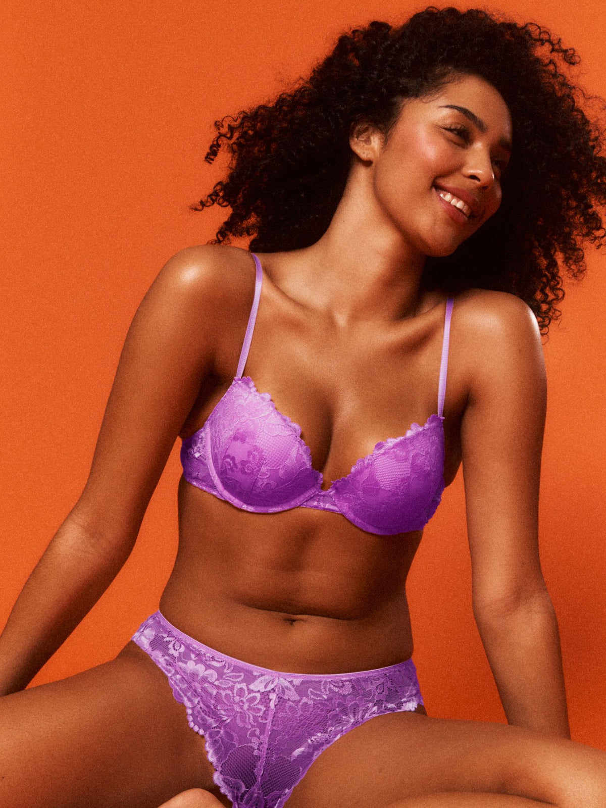 Jaida is wearing a purple bra and panties set against an orange background